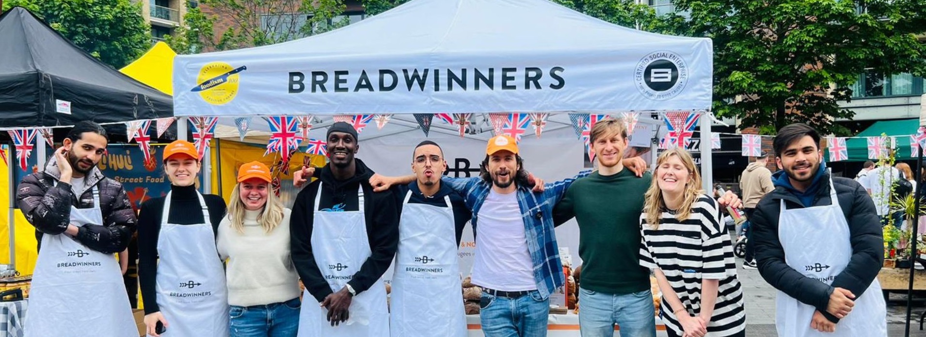 The team from Breadwinners in front of a gazebo featuring their name and the Social Enterprise UK member badge